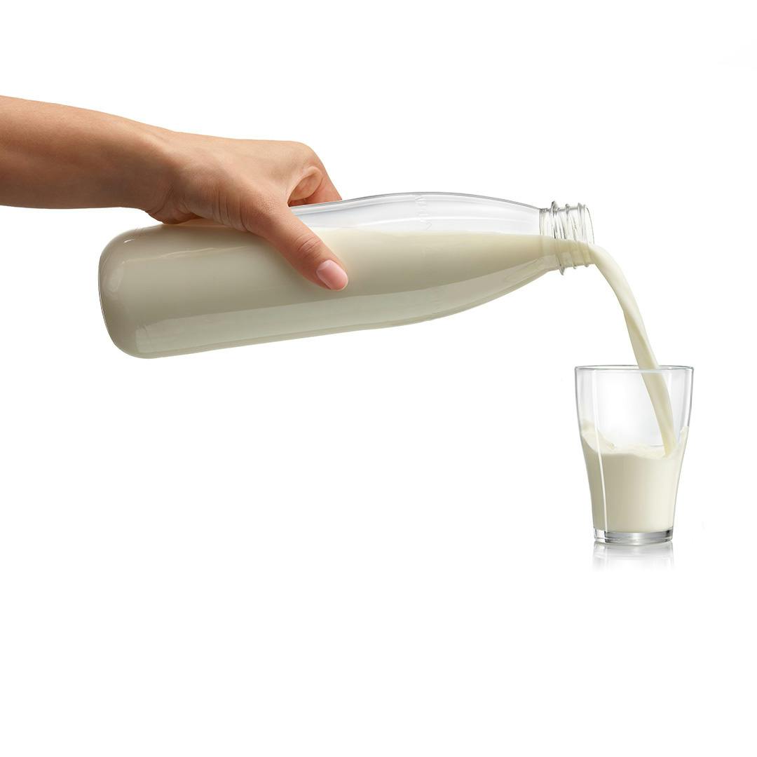 Woman is holding a PET milk bottle and pouring the milk in a glass